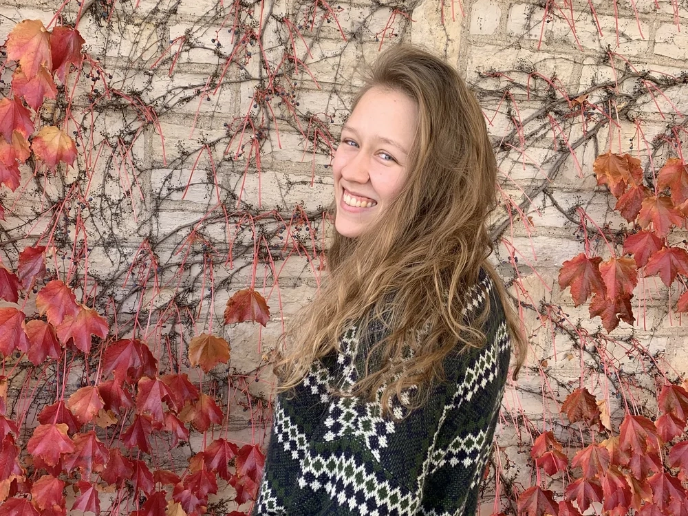 Katharine Weisbrodt, board member, smiling against a backdrop of ivy and leaves